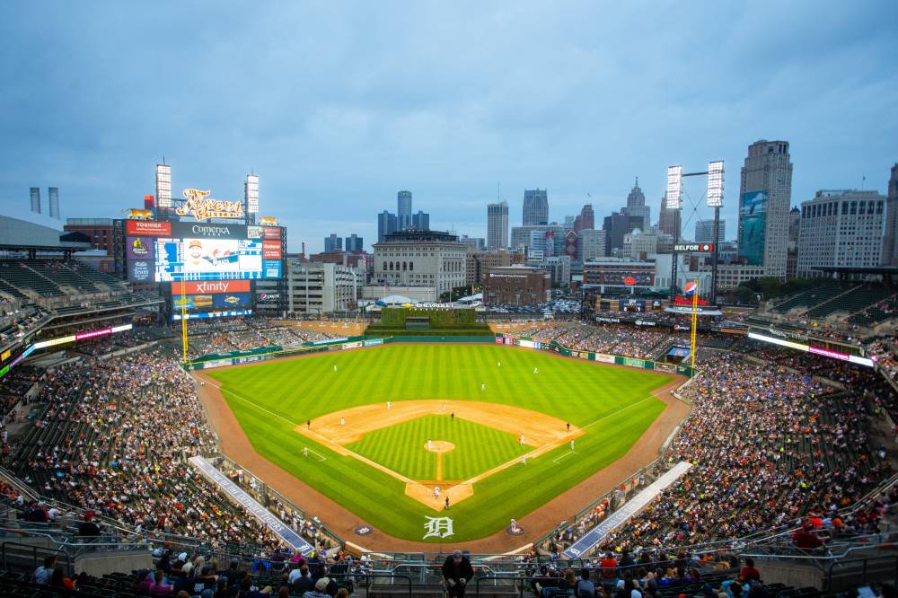 a wide shot from the very top of the stadium. most of the crowd is visible and the players are on the field below. the beautiful Detroit skyline can be seen clearly in the background.